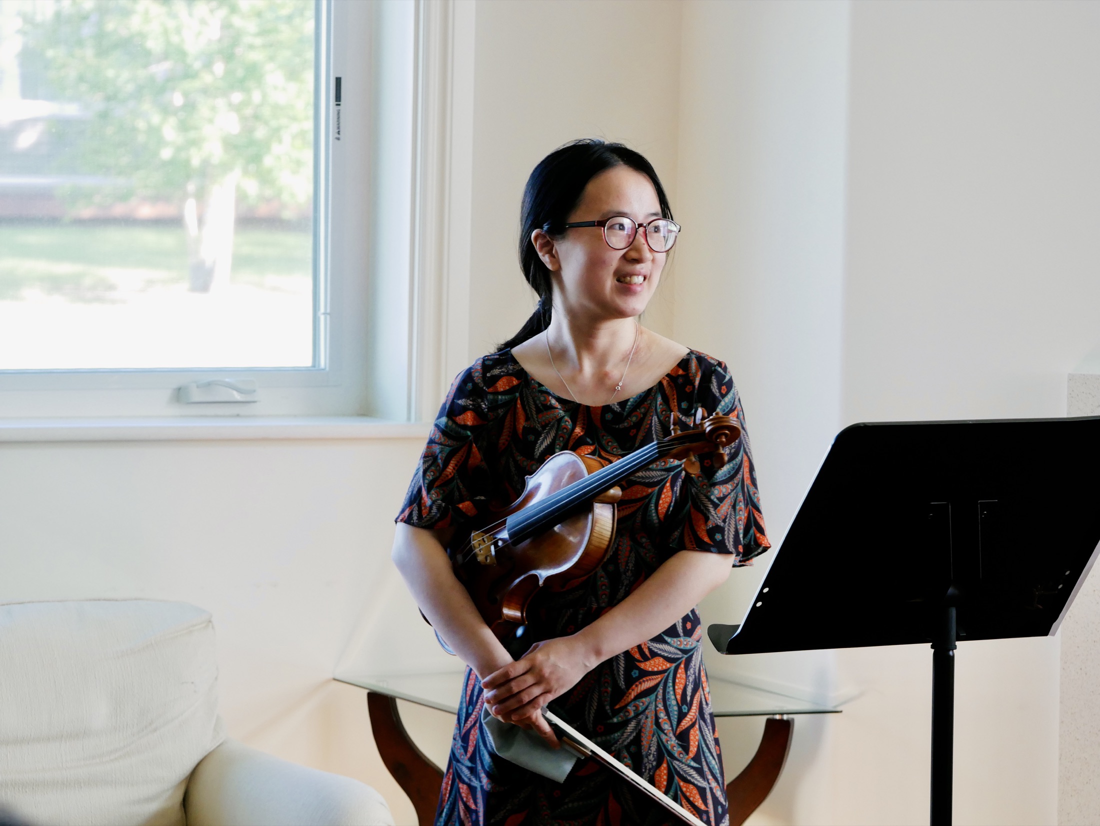 Yue Sun holding her violin in a teaching studio